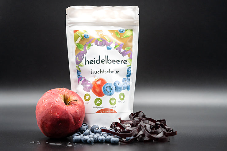 Tüte Fruchtschnüre Sorte Heidelbeere und Heidelbeeren sowie Apfel und daliegende Fruchtschlangen