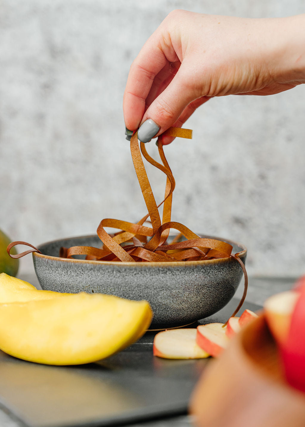 Fruchtschnüre Mango in Schale mit Obst umliegend