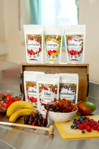 36g Tüten Fruchtschnüre von fruitjunkies in den Sorten Sauerkirsche, Mango, Himbeere, Erdbeere, KiBa, Heidelbeere. Umliegend sieht man Früchte