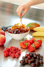 Schale mit Fruchtschlangen und umliegend Früchte wie Bananen, Erdbeeren, Sauerkirschen, Himbeeren, Äpfel, Heidelbeeren und Mango