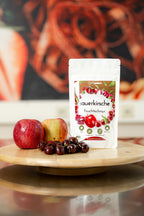 36g Tüte Sauerkirsch Fruchtschnüre auf Drehteller mit Äpfeln und Sauerkirschen