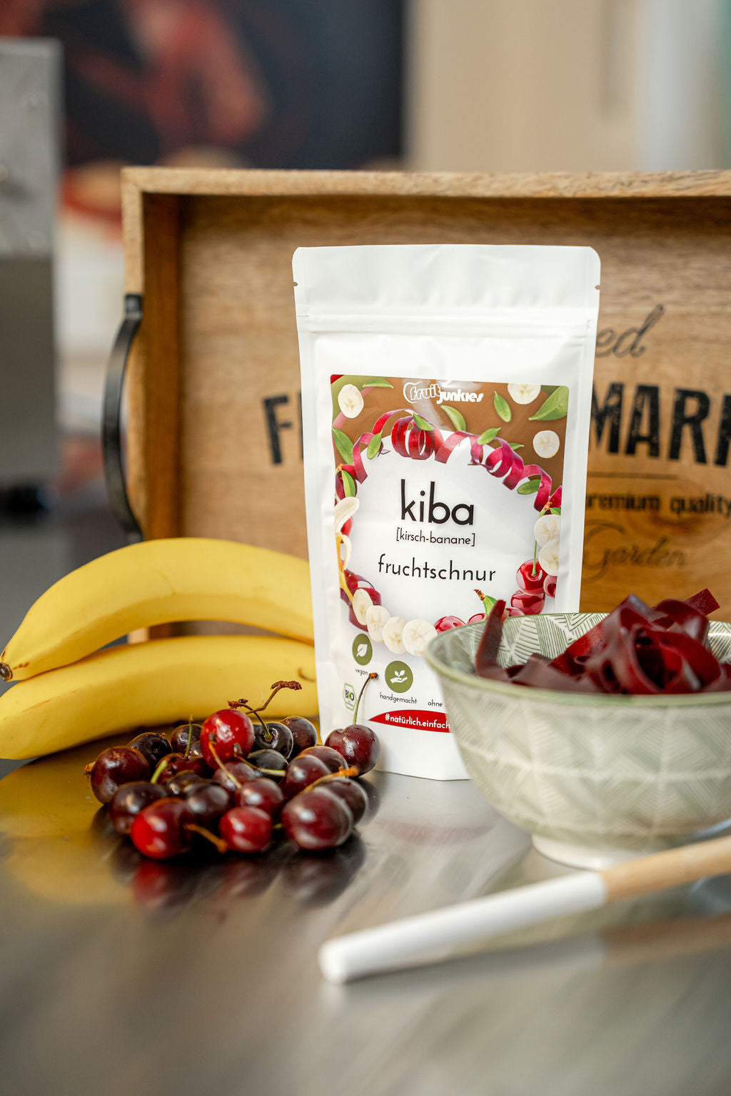 36g Kiba Tüte mit Holzbrett im Hintergrund und Bananen und Sauerkirschen umliegend.